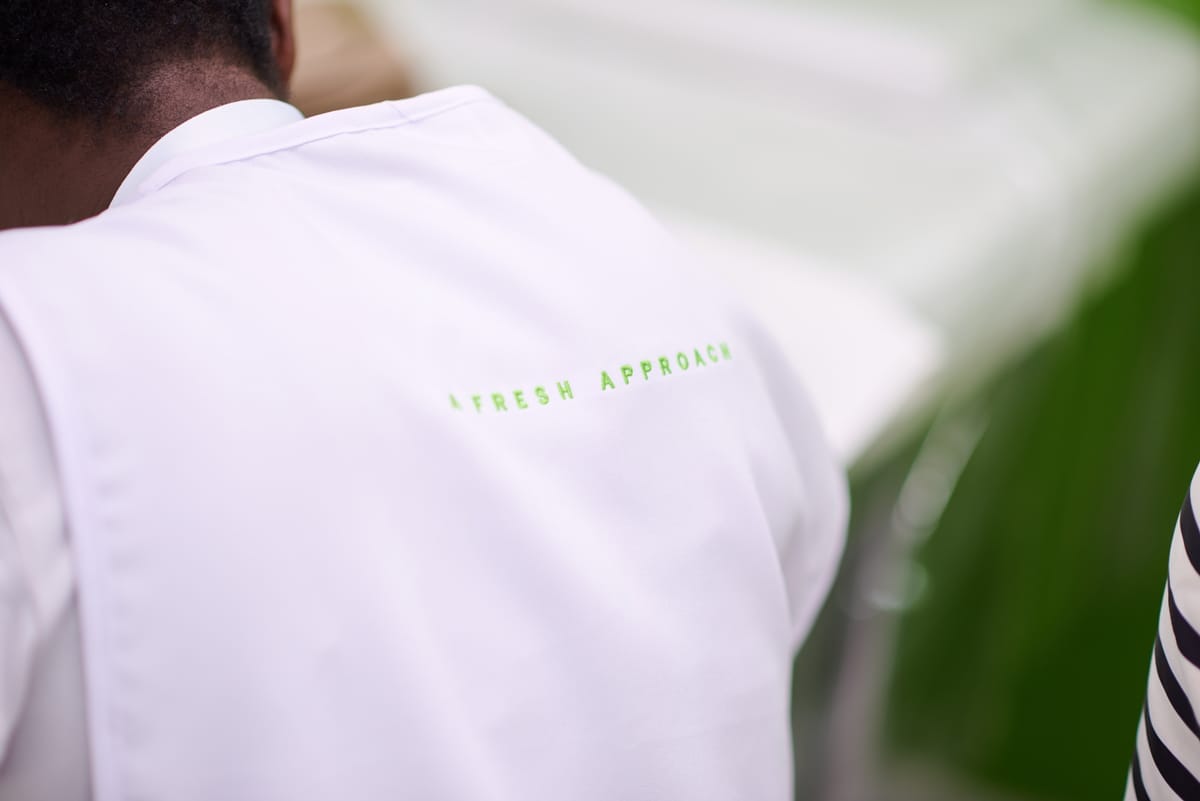 Close-up of a person wearing a white jacket with green text on the back that reads 